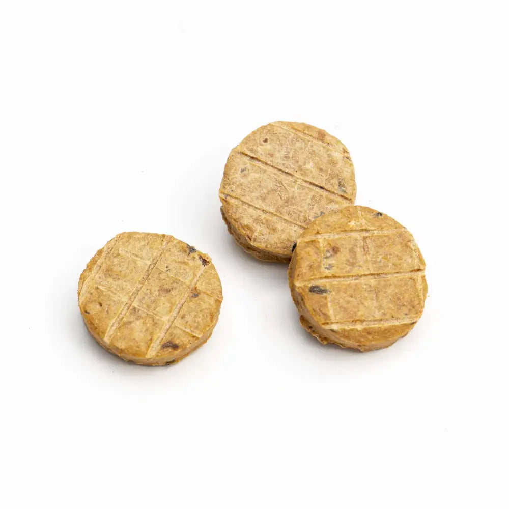 Three round brown dog treats on a white background