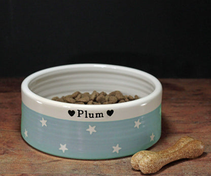 Dog bowl with 'Plum' branding on a wooden surface