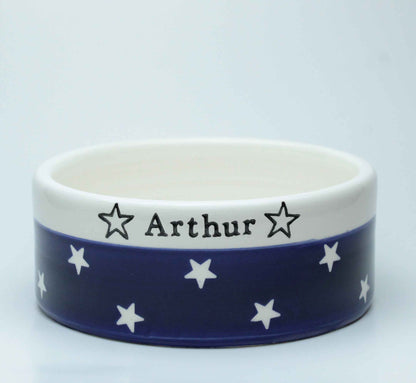 Ceramic bowl with blue band featuring white stars and 'Arthur' text on a white background