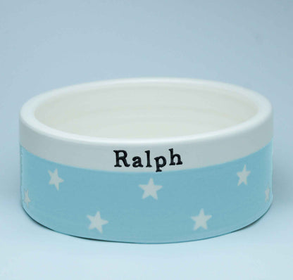 Dog bowl with 'Ralph' printed on it against a light blue background