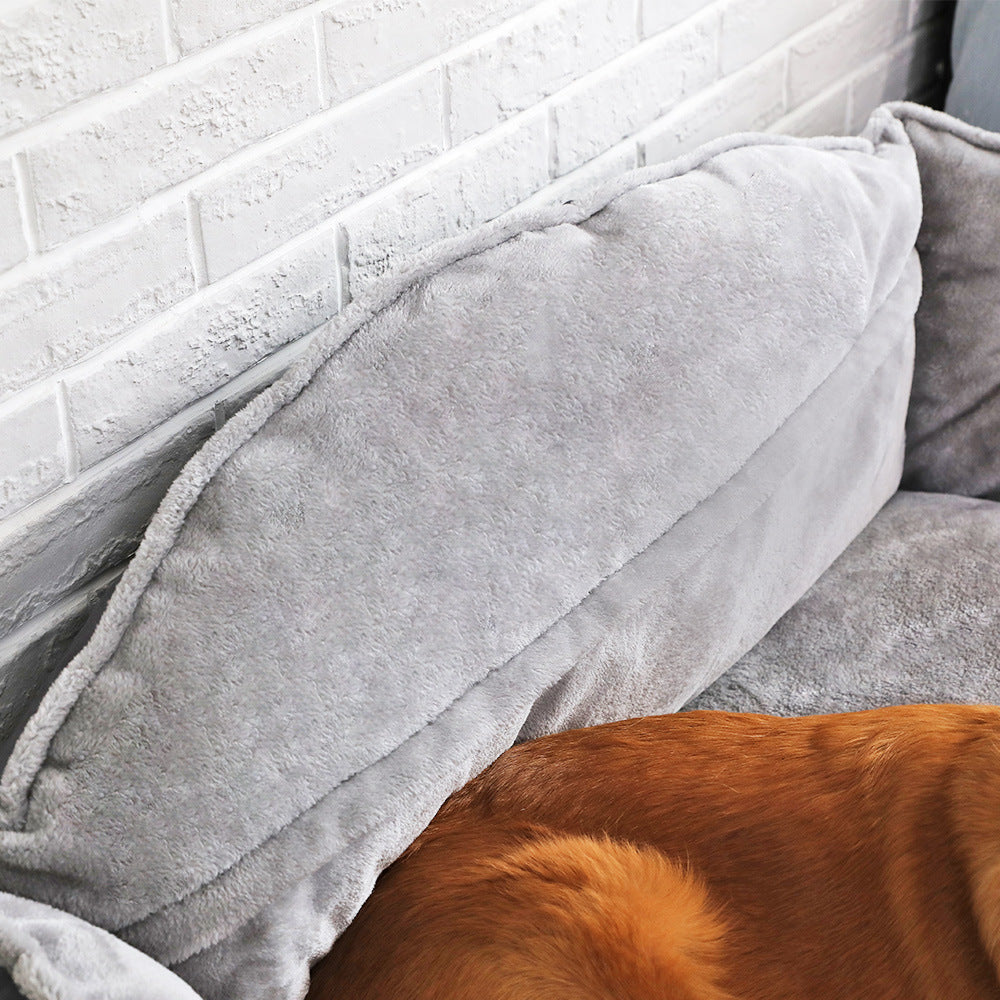  The back of a grey dog bed with a dog partially visible underneath.