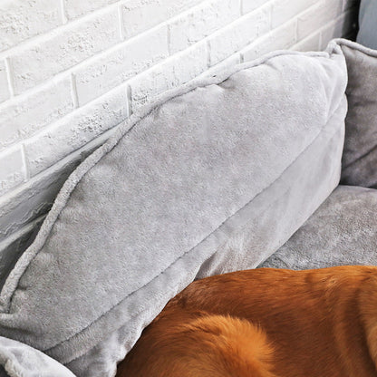  The back of a grey dog bed with a dog partially visible underneath.