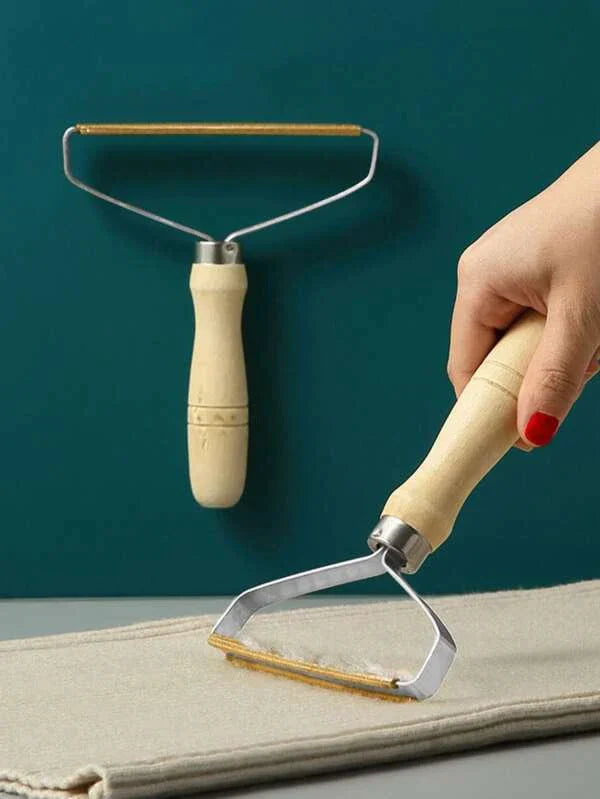 Hand using a pet hair remover on a piece of fabric with a teal background