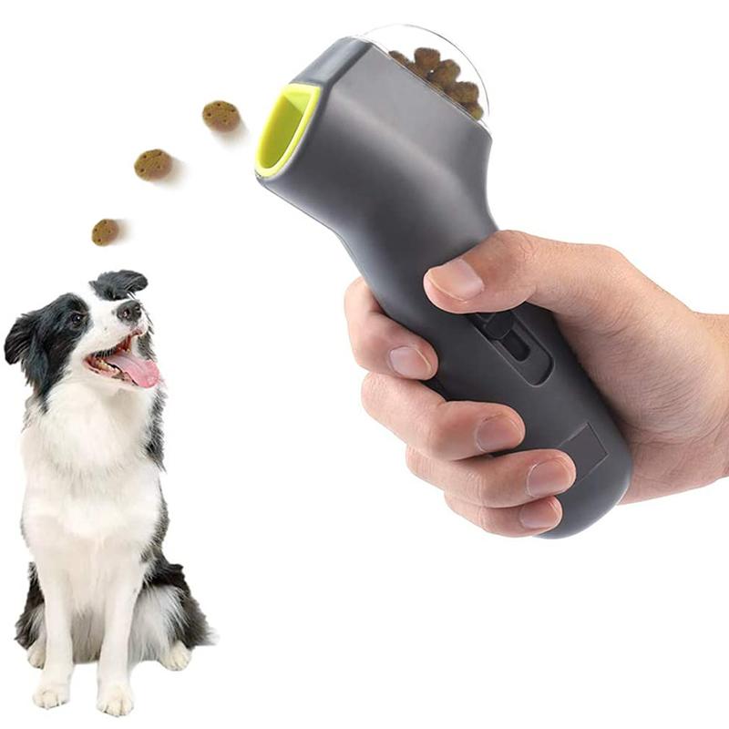 Hand holding a grey pet treat launcher with a dog and scattered treats on a white background