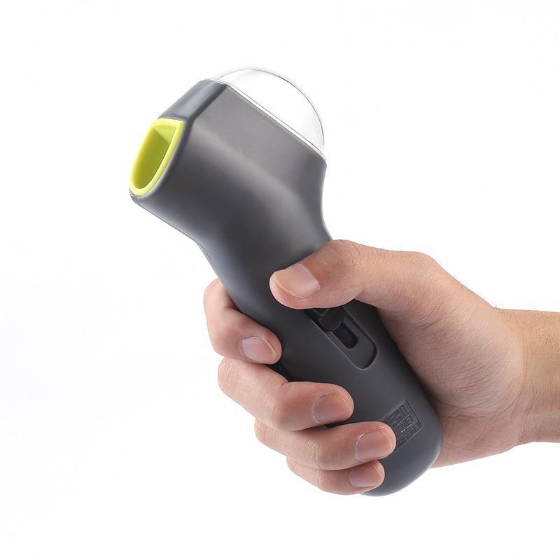 Hand holding a grey and green handheld dog treat launcher on a white background