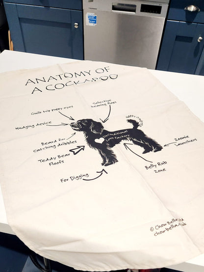 Tea towel with a black and white illustration of a cockapoo and text on a white background.
