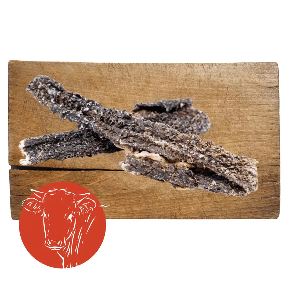 Dried fish on a wooden cutting board with a red circle featuring a cow illustration.