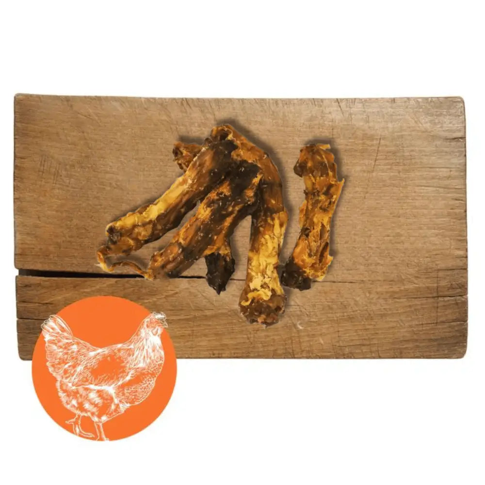 Three dog bones on a wooden cutting board with an orange circle featuring a chicken illustration.