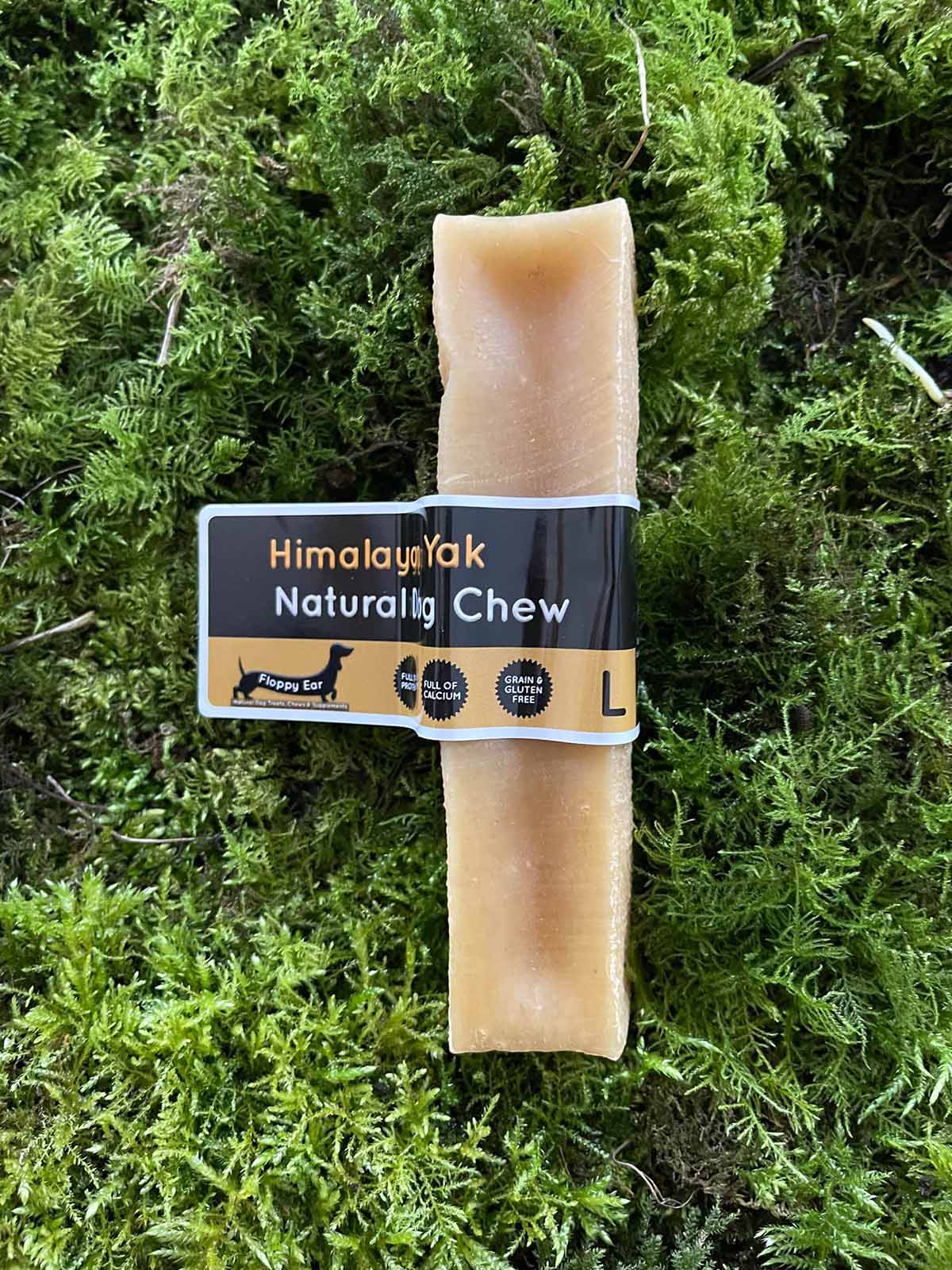 Dog chew treat with 'Himalayan Milk Naturally Chew' label on a green moss background