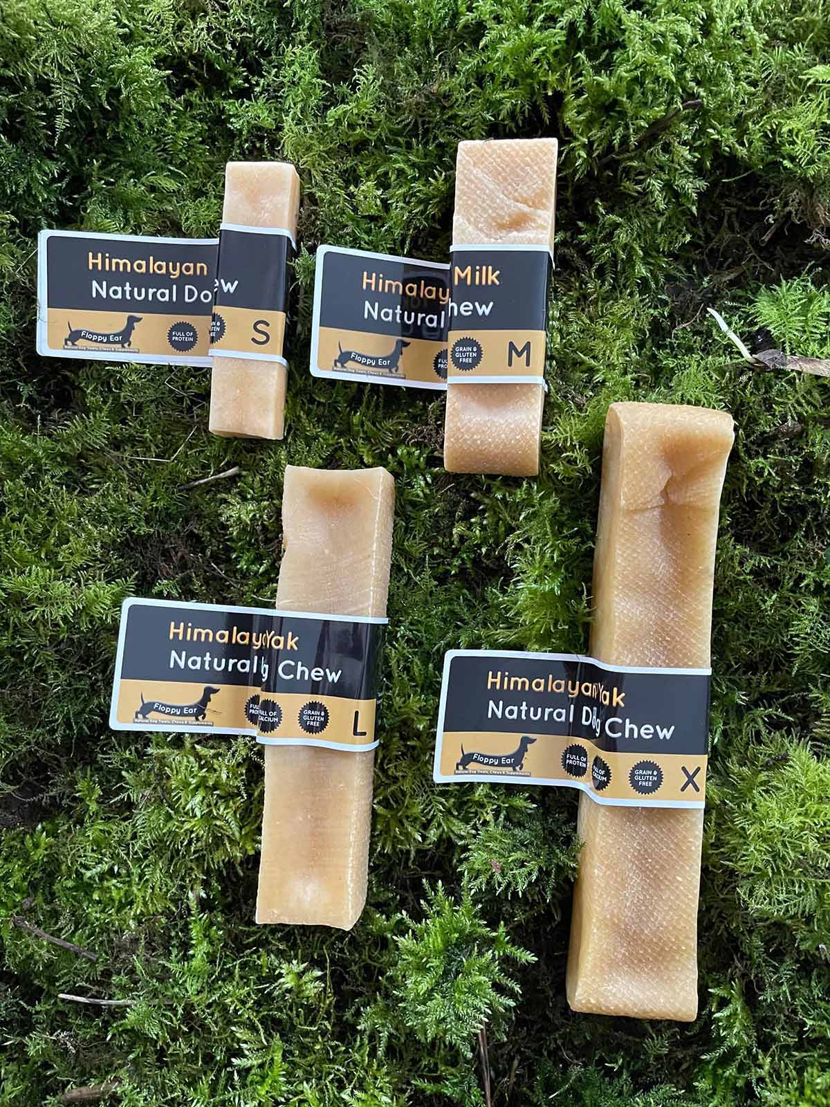 Himalayan Natural Dog Chew packages on a green moss background