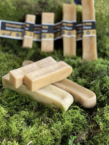 Himalayan Yak Dog Chews on a green mossy surface with more bars and packaging in the background.