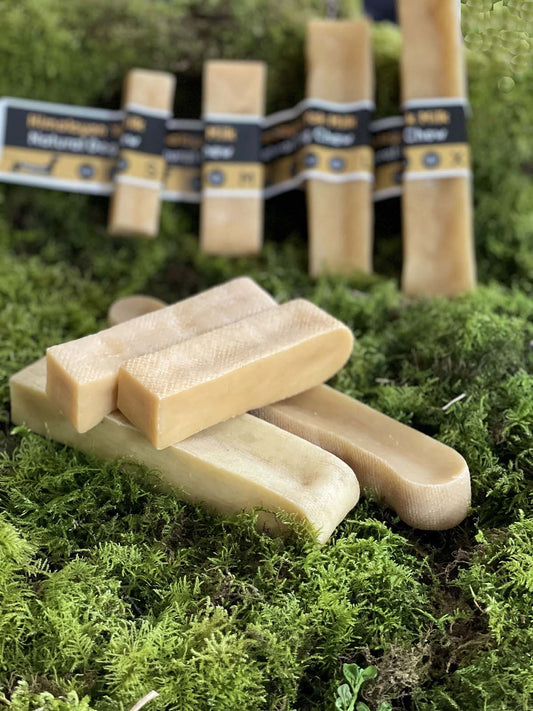 Himalayan Yak Dog Chews on a green mossy surface with more bars and packaging in the background.