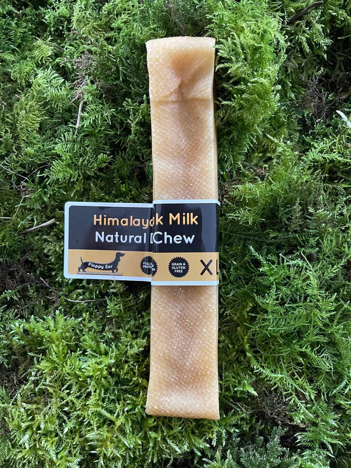 XL dog chew treat with 'Himalayan Milk Natural Chew' label on a green moss background