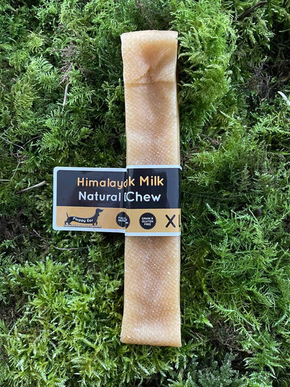XL dog chew treat with 'Himalayan Milk Natural Chew' label on a green moss background