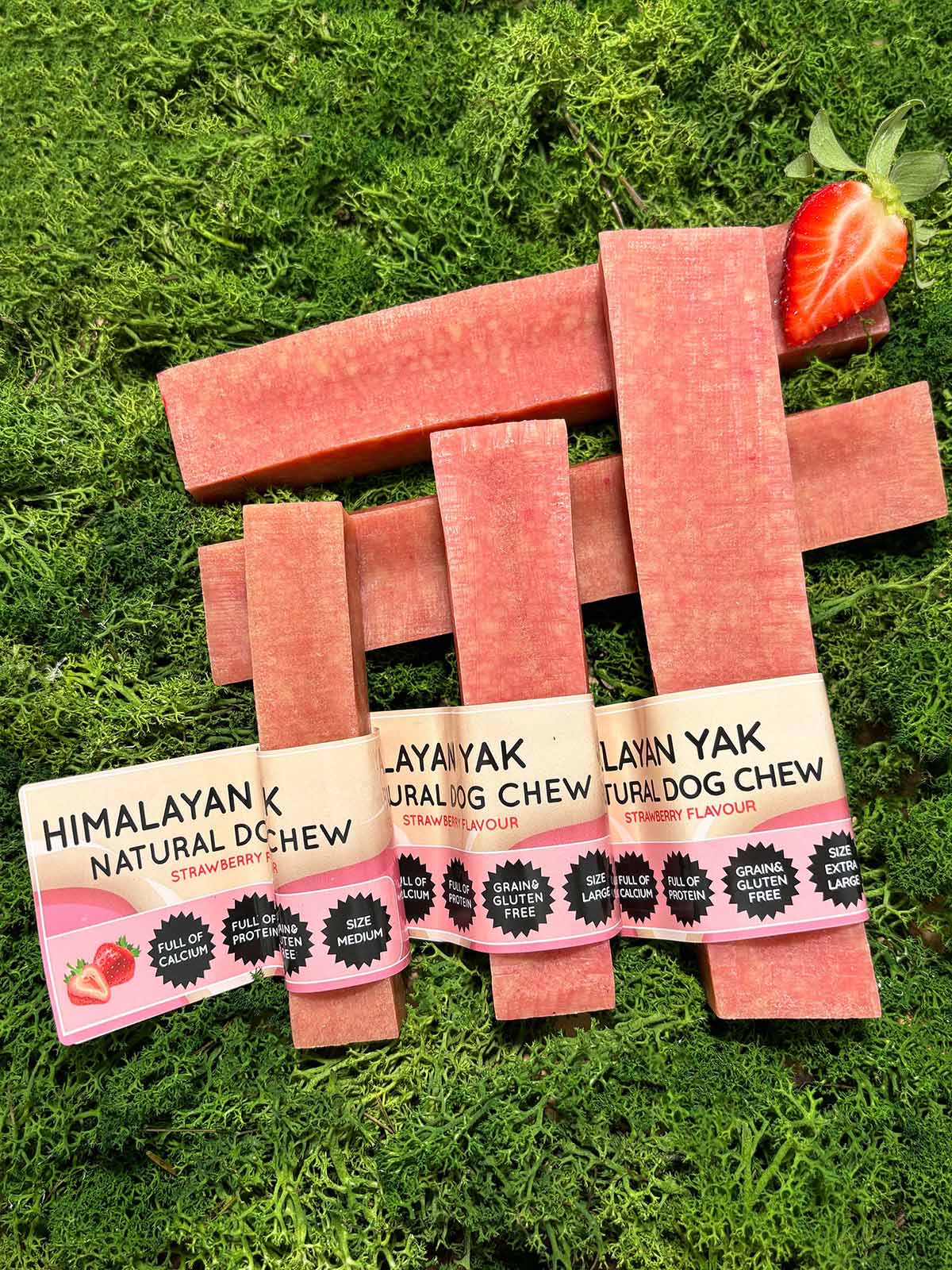 Strawberry flavour Himalayan Yak Natural Dog Chew packaging on grass with a strawberry.