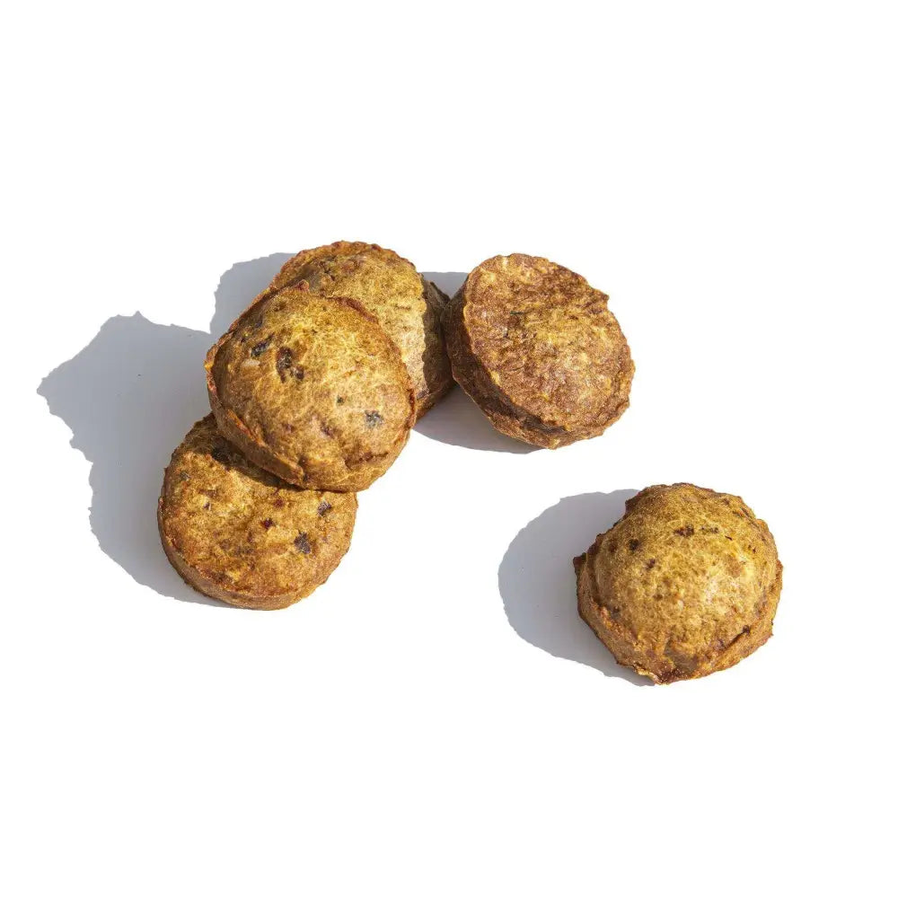 Five round brown dog treats on a white background
