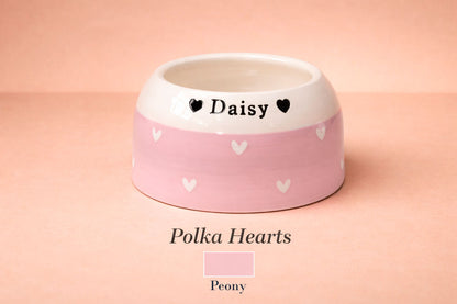 Pink pet bowl with white hearts and 'Daisy' written on a pink background