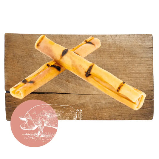 Two dog chew toys on a wooden board with a pink circle and dog illustration in the corner.