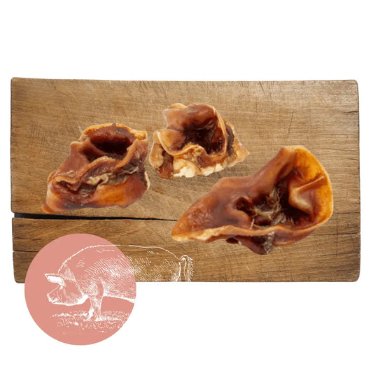 Three pieces of dried beef on a wooden cutting board with a pink circle featuring a bear illustration in the corner.