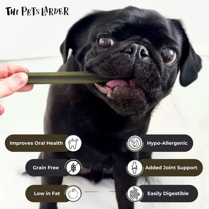 Black dog chewing on a treat with 'The Pet's Larder' branding and product benefits listed.