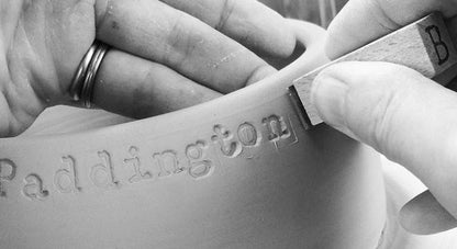 Person engraving 'Paddington' on a surface with a tool.