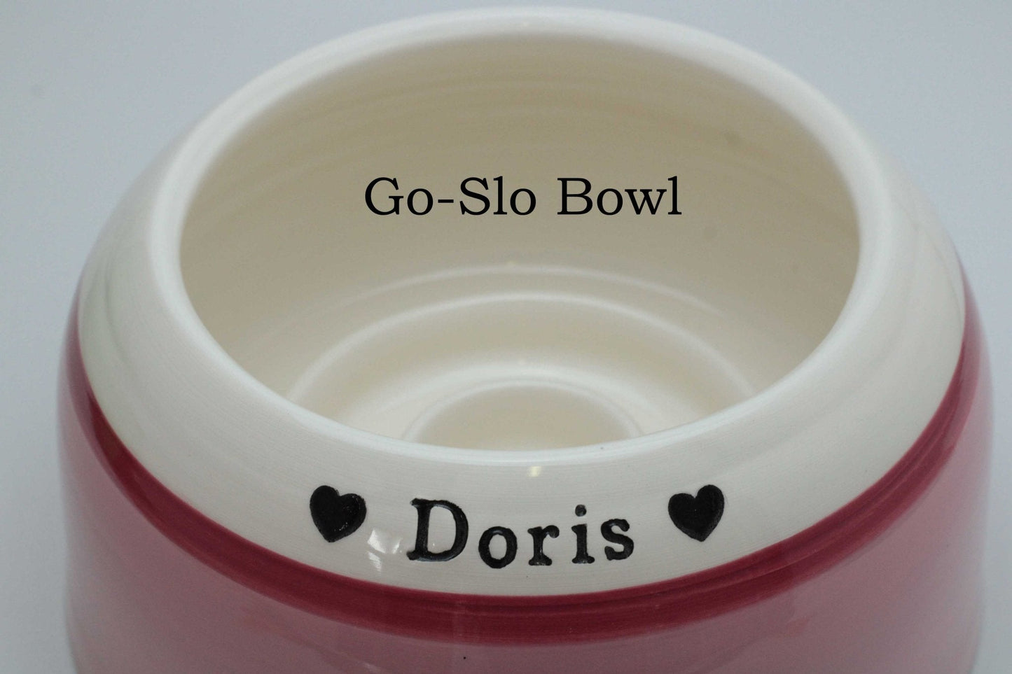 Pink pet bowl with 'Go-Slo Bowl' and 'Doris' text on a white background